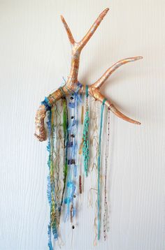 a wall hanging made out of sea glass and shells with beaded strands attached to it