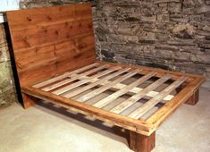 a bed frame made out of pallet wood in front of a stone wall and floor