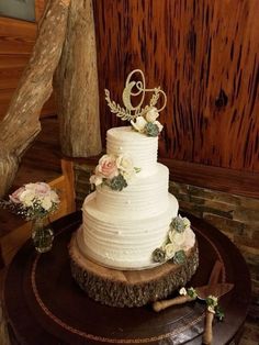 a white wedding cake sitting on top of a wooden table next to a tree stump