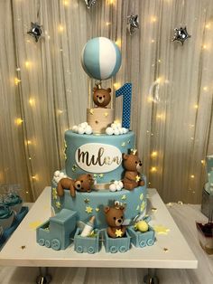 a blue and white cake with teddy bears on it's top is sitting on a table