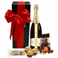 a bottle of wine, chocolates and champagne in a gift box with a red bow