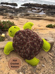 a crocheted turtle sitting on top of a sandy beach