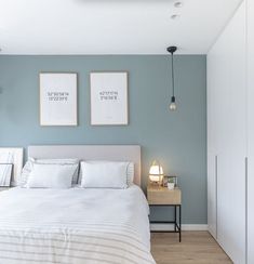 a bedroom with two pictures on the wall above the bed, and a nightstand next to it