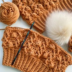 a crocheted hat with two balls of yarn next to it