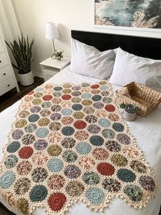 a crocheted blanket on top of a bed with white sheets and pillow cases