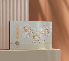 a card with flowers painted on it is sitting on a shelf next to a wall