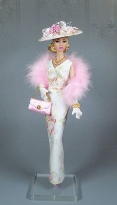 a barbie doll wearing a white dress and pink fur stoler holding a pink purse