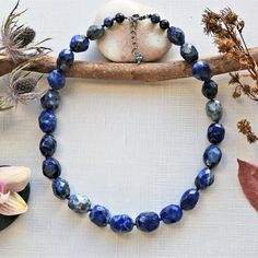 "Necklace length: 18\"L with 1.5\"L extender. Major beads: Lapis lazuli: faceted barrel shaped. Style: Beaded semi-precious stone necklace. Color: Blue color. Clasp: 13MM sterling silver rhodium plated clasp and closed jump ring. Finding: N/A. Workmanship: Hand beaded, and each bead is knotted in dark blue mixed cotton thread. Features: This classic style and timeless necklace feature large faceted lapis lazuli nuggets displaying natural flecks of pyrite that add a hint of shimmer. It is a great Lapis Lazuli Jewelry With Faceted Beads, Adjustable Lapis Lazuli Necklace With Faceted Beads, Adjustable Lapis Lazuli Crystal Necklace, Healing Lapis Lazuli Jewelry With Faceted Beads, Blue Faceted Oval Beads Jewelry, Lapis Lazuli Beaded Necklace With Faceted Beads For Gift, Spiritual Lapis Lazuli Necklace With Faceted Beads, Sapphire Faceted Beaded Necklace For Gift, Faceted Sapphire Beaded Necklace Gift