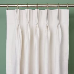 white curtains hanging on a metal rod in front of a green wall with a wooden floor