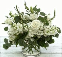 a vase filled with white flowers and greenery