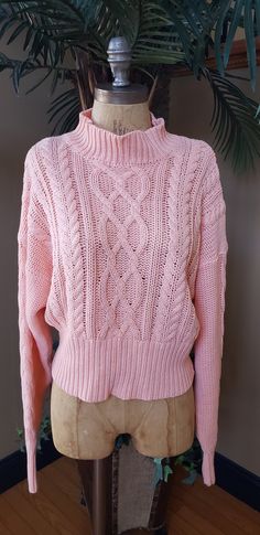 a pink sweater sitting on top of a mannequin next to a potted plant