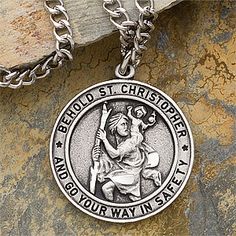 a silver necklace with an image of jesus holding the cross on it's side