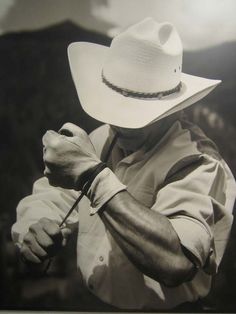 a black and white photo of a man wearing a cowboy hat