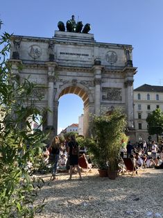 people are walking around in front of an arch