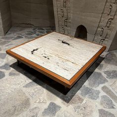 a square wooden table sitting on top of a stone floor