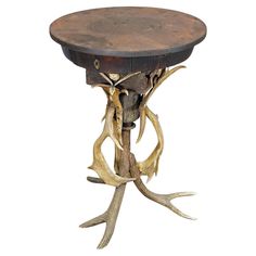 an old wooden table with antlers on it's legs and a round top