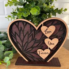 two wooden hearts with the words love you forever written on them sitting next to a potted plant