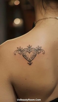 the back of a woman's shoulder with a heart tattoo on her left side