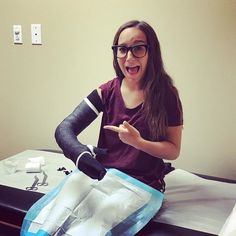 a woman sitting on top of a bed with an arm cast