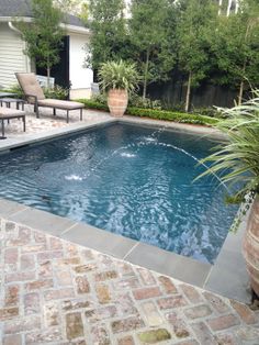 a small pool in the middle of a patio with chairs around it and a large potted plant