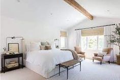 a bedroom with white walls and carpeted flooring has a large bed in the center