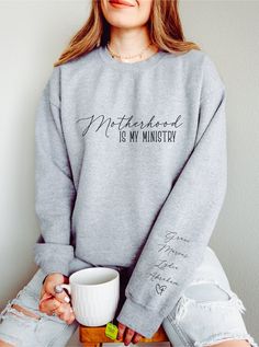 Motherhood is My Ministry Custom Mom Sweatshirt with Kids Name on Sleeve, Homeschool Shirt, Christian Shirts, Christian Mom Gift, Women Gifts Embrace comfort and faith with our Christian sweatshirt. Crafted with the softest materials and featuring timeless designs, this trendy Christian sweatshirt is perfect for expressing your faith while staying cozy. Whether you're lounging at home or heading out, let your style speak volumes with our Motherhood is my Ministry sweater. Features: 1.Premium Com Winter School T-shirt With Letter Print, Casual Cotton Sweatshirt With Name Print, Oversized Cotton Sweatshirt For School, Winter School Sweatshirt, Pre-shrunk, School Spirit Cotton Sweatshirt With Name Print, Cotton Sweatshirt With Name Print For School Spirit, Winter Letter Print T-shirt For School, Christian Mom Gifts, Homeschool Shirts