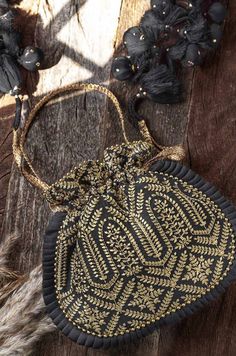 "Our Leela heritage potli is pure class and opulence. The beauty lies in heavy detailed handcrafted tassles that add the weight to this potli and will charm everyone off their feet! Colour: Black with gold embroidery Embroidered front and back. Dimensions (LxB): 8.5\"×9.5\"  Handle drop: 5\" Material : Embroidered poly silk, gold tissue, poly satin lining, woven gold thread drawstrings and woven drawstring handle, handcrafted tassels." Prom Bag, Embroidered Clutch, Potli Bags, Functional Fashion, Gold Embroidery, Bride Clothes, Gifts For My Sister, Gold Threads, Evening Clutch Bag