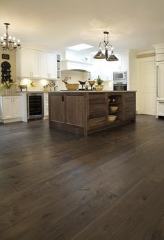 a large kitchen with white cabinets and wood flooring in it's center island