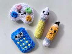 three crocheted cell phones with faces on them