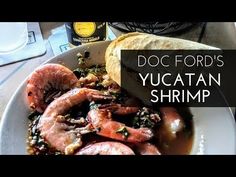 a bowl filled with food next to a sandwich on top of a table and the words doc ford's yuctan shrimp