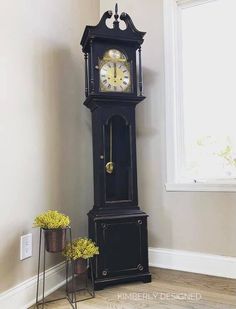 a tall black grandfather clock sitting in the corner of a room next to a window