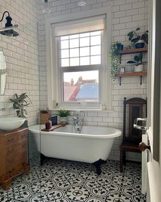 an old fashioned bathtub in a bathroom with black and white floor tiles on the walls