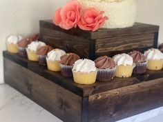 cupcakes are lined up on a wooden stand