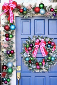 a christmas wreath on the front door of a house with ornaments hanging from it's sides