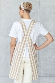 a woman standing with her back to the camera wearing a tan and white checkered apron