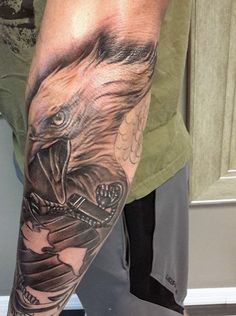 a man with a tattoo on his arm has an eagle holding a snake in it's mouth