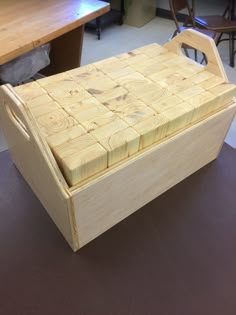 a wooden box sitting on top of a floor next to a table with chairs in the background