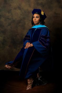 a woman in a graduation gown and cap poses for a photo with her hand on her hip