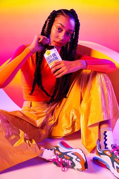 a woman sitting on the ground with her legs crossed and holding a bottle of milk