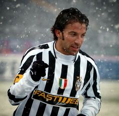 a man in black and white uniform holding a soccer ball on a field with snow falling around him