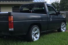 a black truck parked in the grass near a house