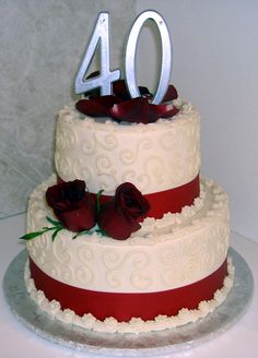 a white and red wedding cake with roses on top