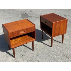 two wooden nightstands sitting side by side on cement ground with one drawer open and the other closed