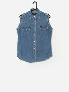 Vintage Lee Union Made sleeveless denim shirt. This 80s/90s fitted denim shirt vest features two chest pockets with snap button closures, a snap button closure and is made from a lightweight soft cotton.  Our recommended size: Medium Label says: Medium Condition: Very good  Material: 100% cotton Measurements in inches: Pit to pit: 19.5 Shoulders: 14 Front length: 26.5 Back length: 27 We recommend that you compare our measurements to a similar item of your own to ensure good fit. Measurements are Sleeveless Cotton Denim Jacket With Button Closure, Casual Sleeveless Denim Jacket With Button Closure, Sleeveless Denim Blue Jacket With Button Closure, Sleeveless Denim Jacket With Button Closure, Casual Denim Sleeveless Vest With Snap Buttons, Casual Sleeveless Denim Jacket With Buttons, Sleeveless Denim Top With Pockets, Casual Medium Wash Button-up Vest, Sleeveless Denim Blue Top With Buttons