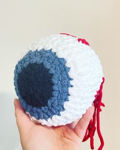 a hand holding a crocheted object with red, white and blue yarn on it