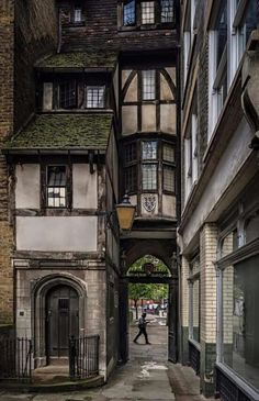 a person walking down an alley way between two buildings with arched doorways on either side