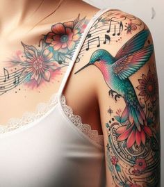 a woman with tattoos on her chest and shoulder is wearing a white tank top that has colorful flowers, music notes, and a humming