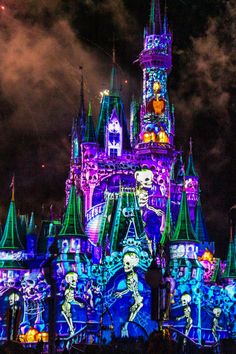 the castle is lit up at night with colorful lights on it's sides and skeleton decorations