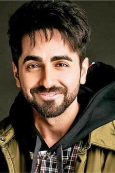 a man with a goatee and beard smiling at the camera while wearing a jacket