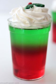 red, green and white jello in cups with whipped cream on the rims